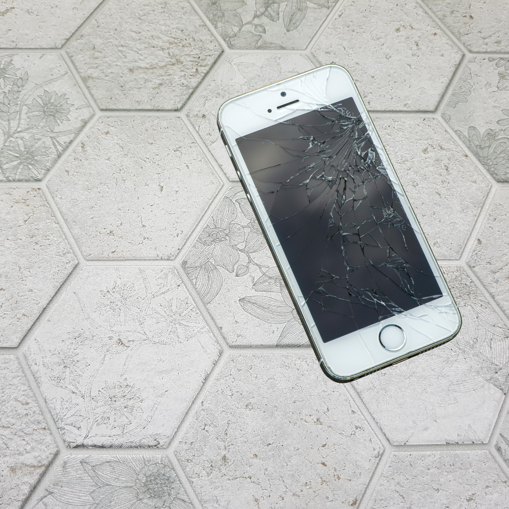Smartphone with a cracked screen on a textured gray surface