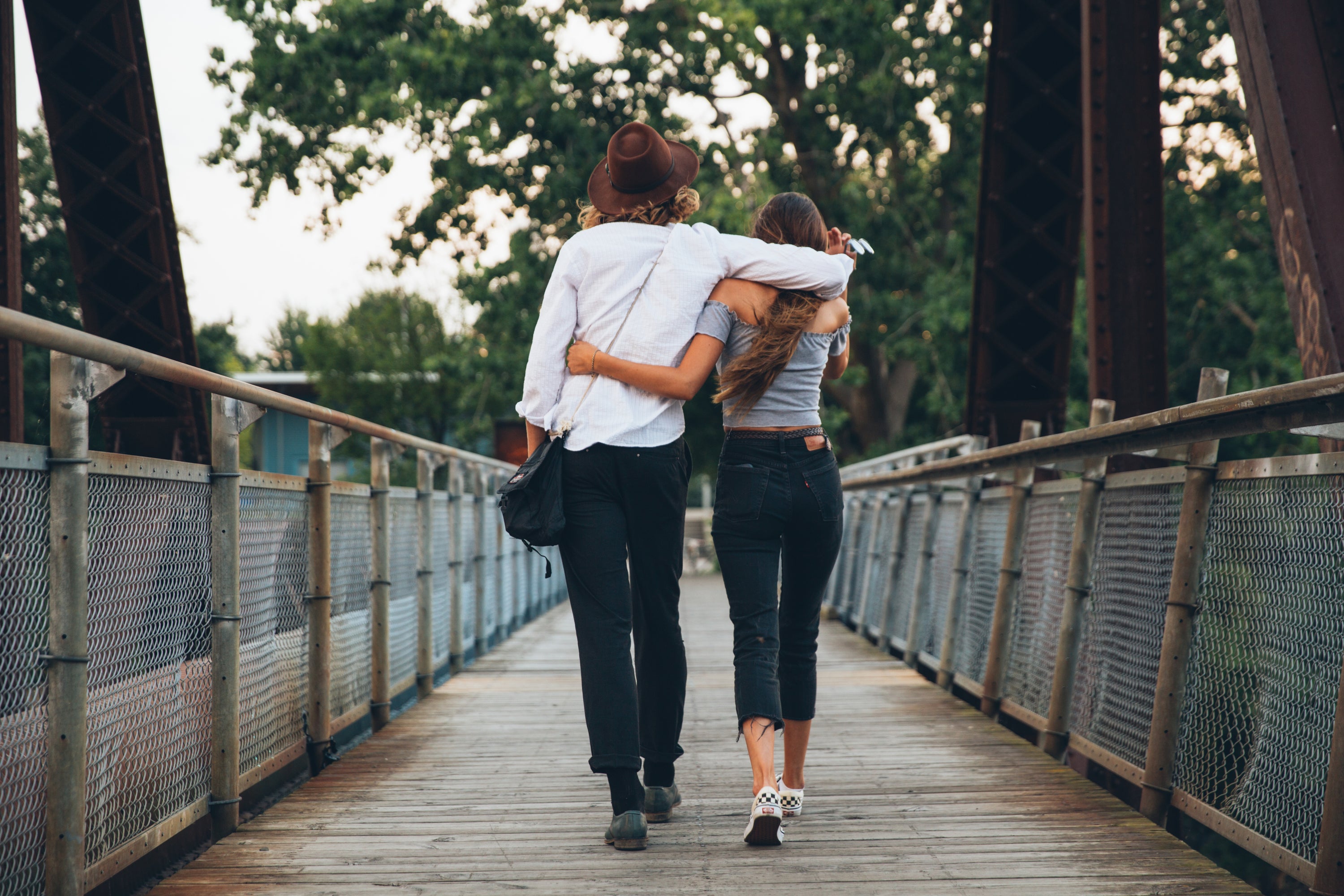 A couple walking over a bridge with their arms around each other