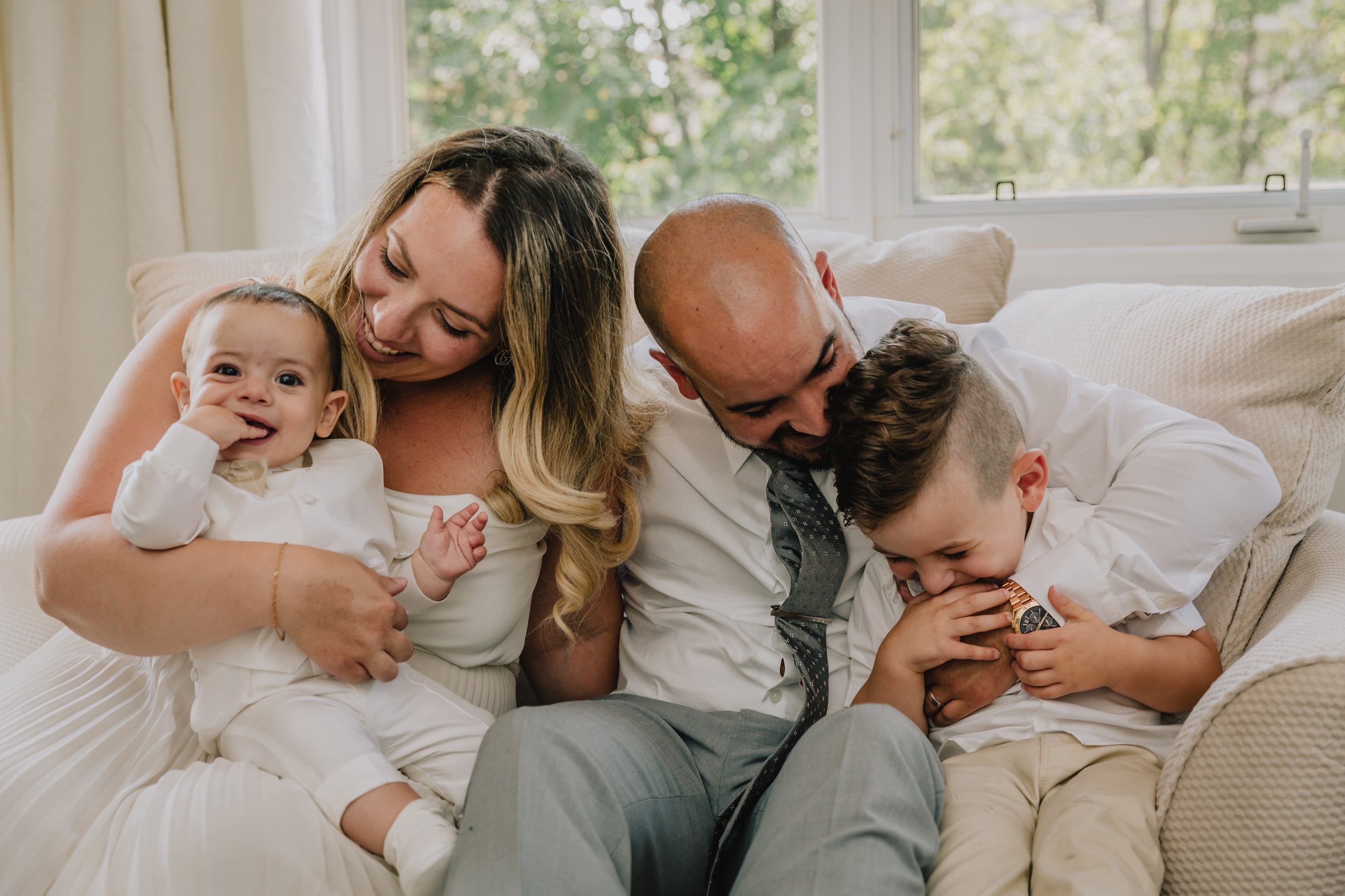 A young family sitting on a couch hugging each other