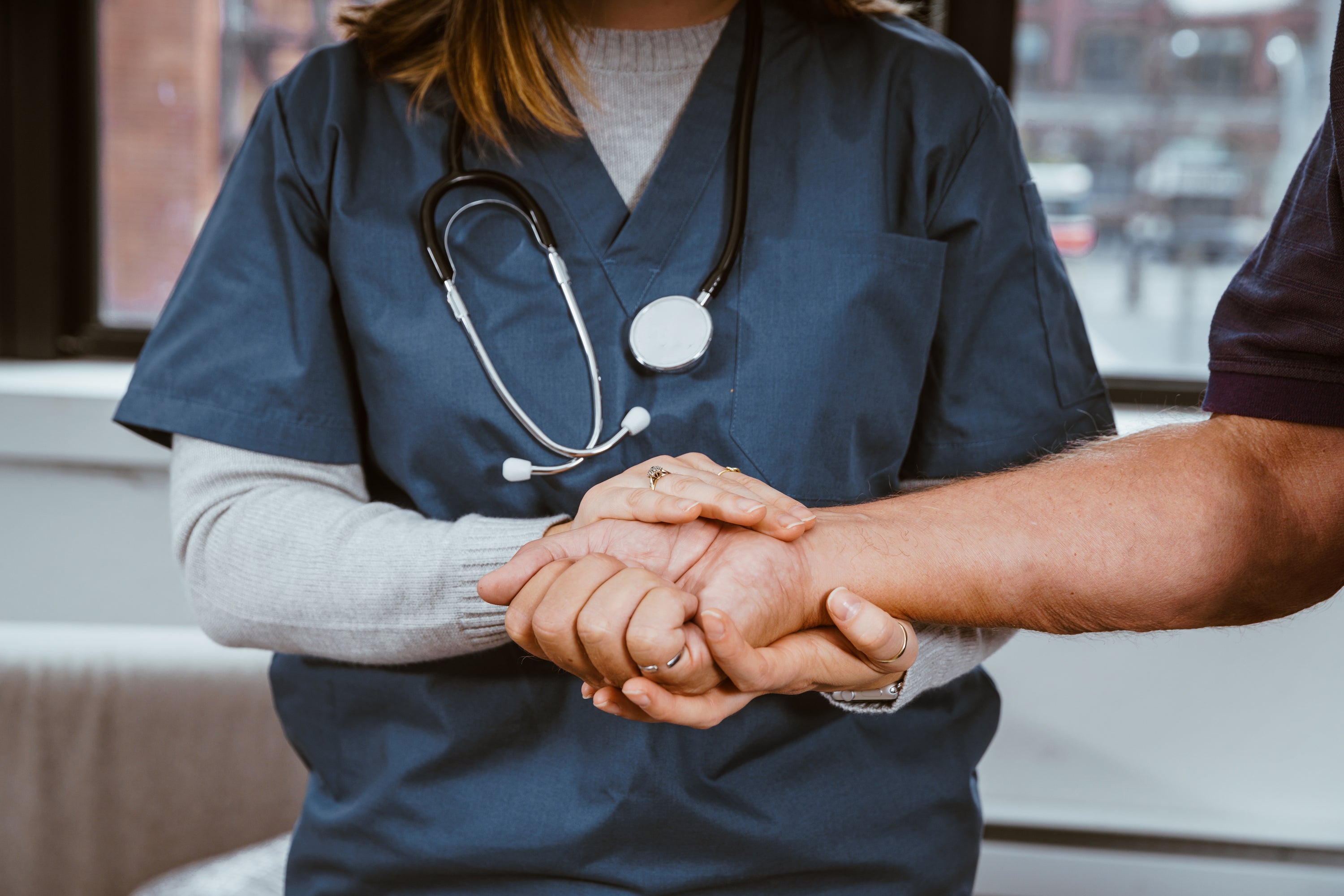 A nurse holding a patient's hand